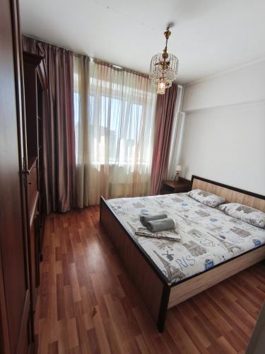 a bedroom with a bed and a chandelier at Xata 1+2 in Almaty