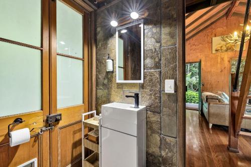 a bathroom with a white refrigerator and a stone wall at Cascade Springs in North Tumbulgum