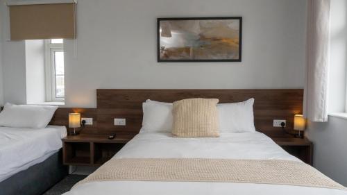 two beds in a bedroom with two lamps on them at The Watling Inn in Nuneaton