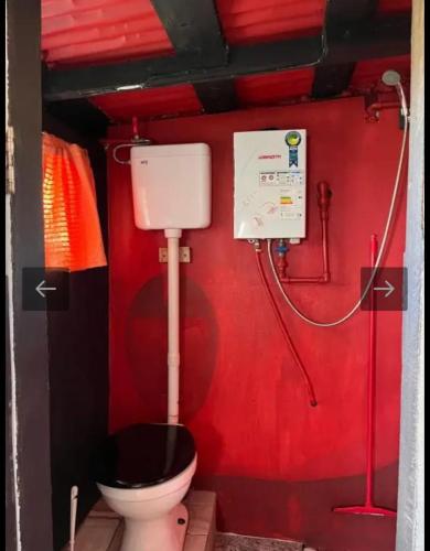 a bathroom with a toilet and a red wall at Casa Sur in Cabo Polonio