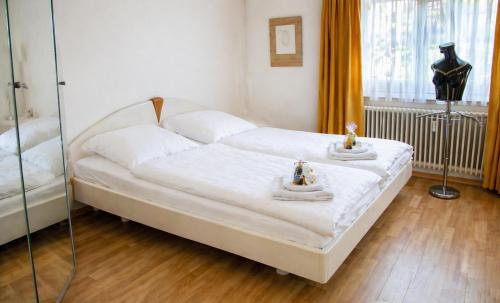 a bedroom with a white bed with two figurines on it at Ferienwohnung -West Häfele Blick in Hagnau