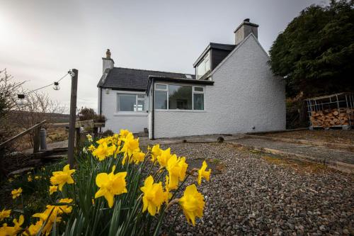 a house with yellow flowers in front of it at Ard Dhub House Your 3 Bedroom cottage retreat in Waternish in Hallin