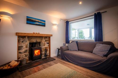 a living room with a couch and a fireplace at Ard Dhub House Your 3 Bedroom cottage retreat in Waternish in Hallin
