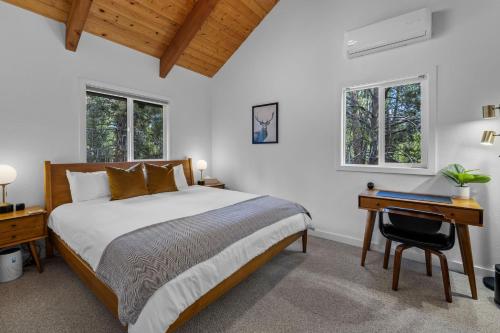 a bedroom with a bed and a desk and two windows at Three Rivers Basecamp - Meredith Lodging in Sunriver