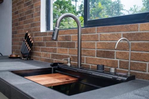 a kitchen sink with two faucets and a brick wall at Margaritas House in Buenos Aires