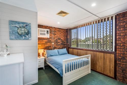 a small bedroom with a bed and a window at Deco Beach - 9 Cedar Street in Evans Head
