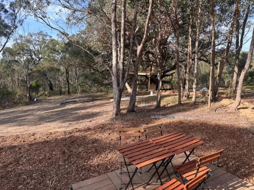 a wooden picnic table and benches in a park at Tiny House Adventure by Tiny Away in Tallarook
