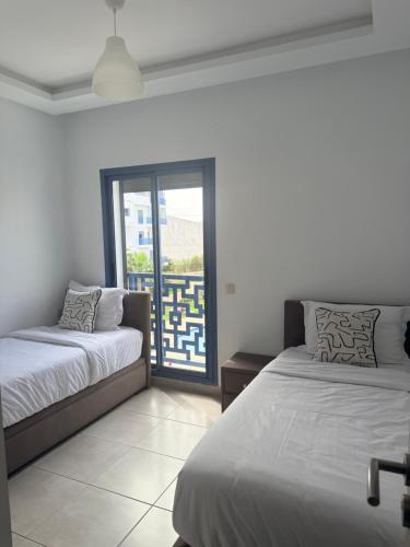a bedroom with two beds and an open window at Luxury Apartment in martil in Martil
