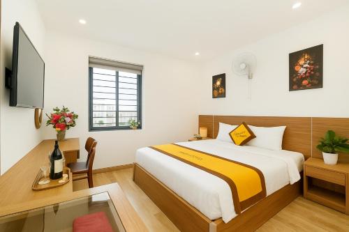 a bedroom with a bed and a desk and a tv at Sonne Hotel Quang Binh in Dong Hoi