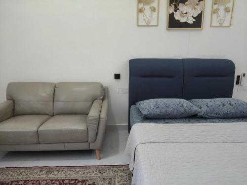a bedroom with a couch next to a bed at Makwan Homestay D in Kubang Semang
