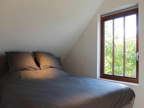 a bed in a room with a window at Valomerius Charming holiday home in Maarkedal