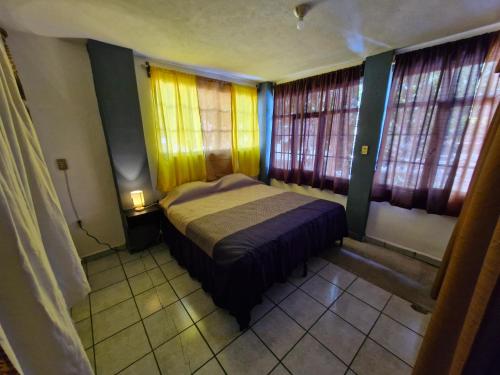 ein kleines Schlafzimmer mit einem Bett und einigen Fenstern in der Unterkunft Casa Nicolette in Uruapan del Progreso