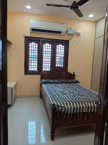 a bedroom with a bed with a fan and a window at Sri Durga Nilayam in Bhadrāchalam