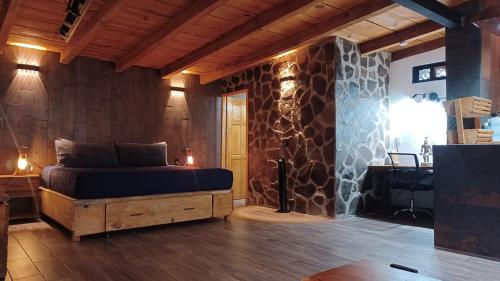 a bedroom with a bed and a stone wall at Mazamitla Pinos del Rio in Mazamitla