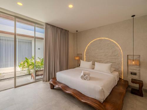 a bedroom with a large bed and a large window at Kala Lombok Hotel in Kuta Lombok