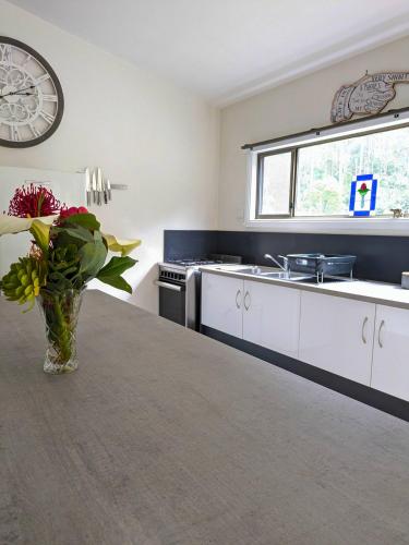 a kitchen with a vase of flowers on a table at Friends With Bienefelts in Turners Beach