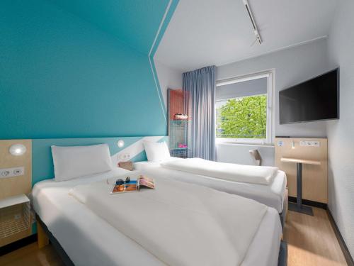 two white beds in a room with a blue wall at Ibis Budget Leipzig City in Leipzig