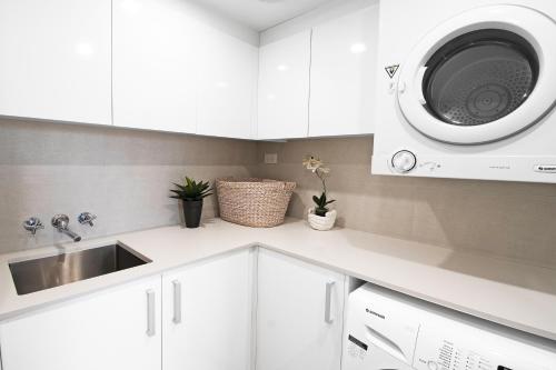 a kitchen with white cabinets and a washing machine at Ocean Sands Resort in Gold Coast