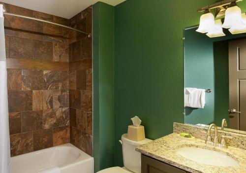 a bathroom with green walls and a tub and a sink at Hilton Grand Vacations Christmas Mountain Village Wisconsin in Wisconsin Dells