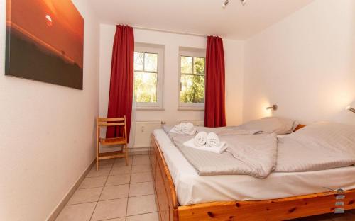 a bedroom with a bed and a window with red curtains at Wattschnecke in Böhl