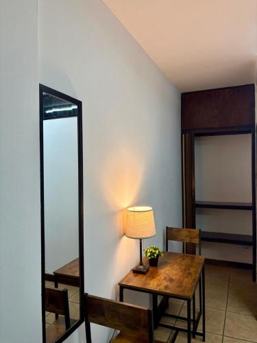 a room with a table with a lamp and a mirror at Luca in San José