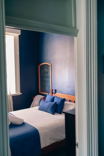 a bedroom with blue walls and a bed with blue pillows at The Great Central Hotel in Glen Innes