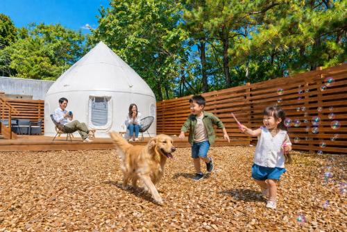 three children playing with a dog in front of a tent at ReSchool Nasu Glamp in Nasu