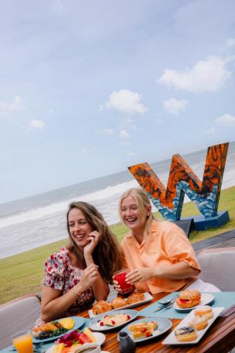 two women sitting at a table with food at the beach at W Bali - Seminyak in Seminyak