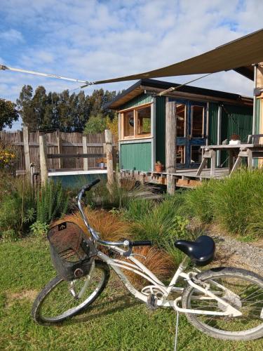 a bike parked in the grass in front of a house at Freefall Cottage in Haumoana