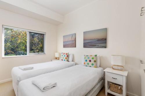 two beds in a white room with two windows at Indigo Blue in Robe