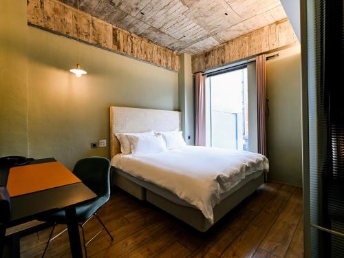a bedroom with a bed and a desk and a window at CHECK inn HIVE in Luodong