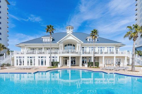 a large white house with a pool in front of it at 2BR Beach Condo Shared Pool Tennis Courts in Gulf Shores