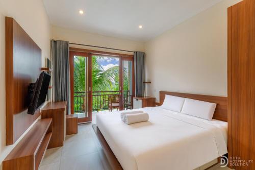 a bedroom with a large white bed and a window at Sedana Cottage in Canggu