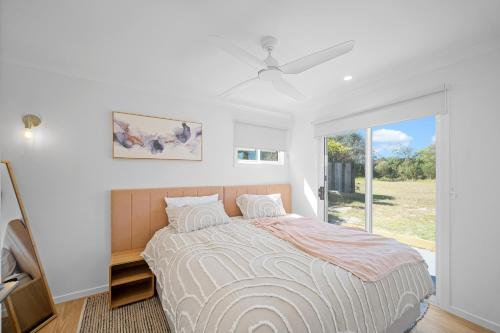 a white bedroom with a bed and a window at The Lookout in Diamond Beach