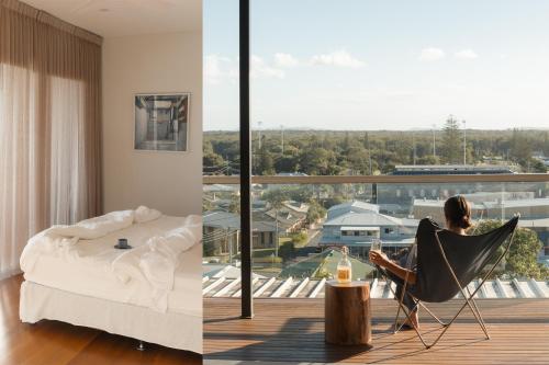a woman sitting in a chair looking out of a window at Bay Properties The Chill in Yamba