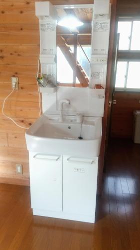 a white bathroom with a sink and a mirror at のんびれっじひなぎくａ棟 in Anazawa