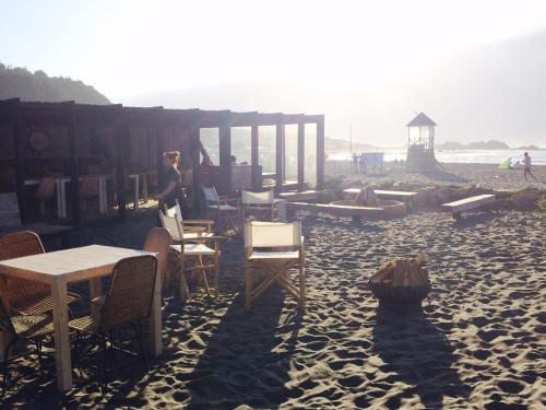a woman standing on a beach with tables and chairs at Casa Mirador Roca in Matanzas
