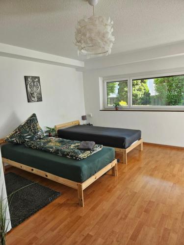 two beds in a room with wood floors and a chandelier at Premium Home 2 in Busingen am Hochrhein