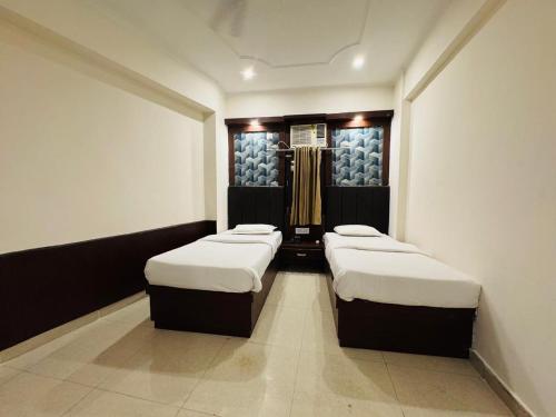 a room with three beds in it with a closet at Hotel Ganga Aatitheyam in Haridwār