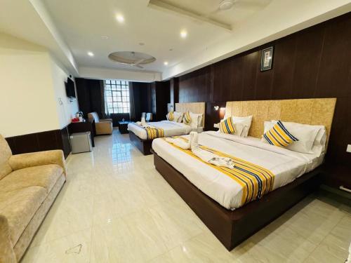 a hotel room with two beds and a couch at Hotel Ganga Aatitheyam in Haridwār