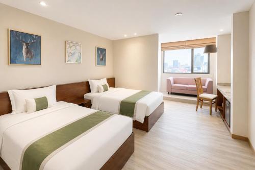 a hotel room with two beds and a chair at Clover Hotel Monivong in Phnom Penh