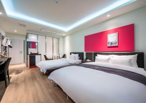 a hotel room with two beds and a red wall at Gimpo Pentastar Hotel in Gimpo