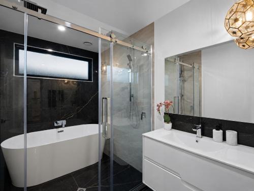 a bathroom with two sinks and a glass shower at The Gem - 5 bedroom brand new house in Christchurch