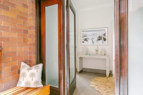 a hallway with a mirror and a brick wall at Manly Beachfront Stays - 3 Bedroom with Garden - Steps to Ferry, Beach, Shops & Restaurants in Sydney