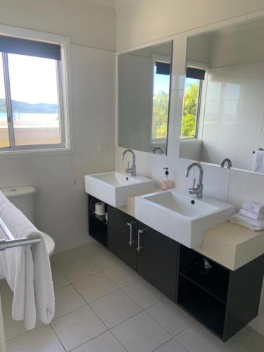 a bathroom with two sinks and a large mirror at Airlie Apartments in Airlie Beach