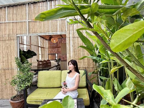 a woman sitting on a chair on a patio at Jazz Living - Tropical Apartment 5 minutes walk from landmark 81 in Ho Chi Minh City