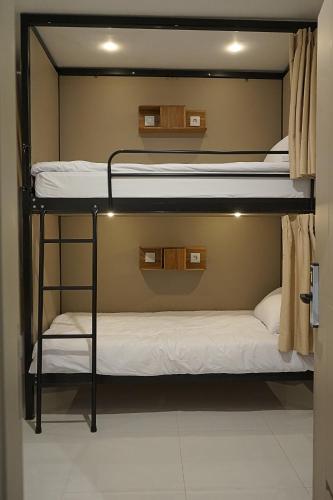 two bunk beds in a room with white sheets at New Hostel Braga in Bandung