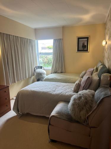 a bedroom with two beds and a couch and a window at Coppelia Sunrise in Omokoroa