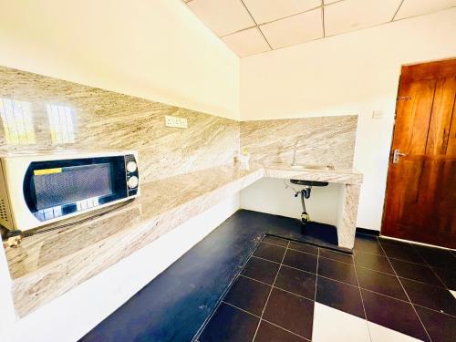 a kitchen with a counter and a microwave on a wall at Oli Guest House Diyathalawa in Diyatalawa