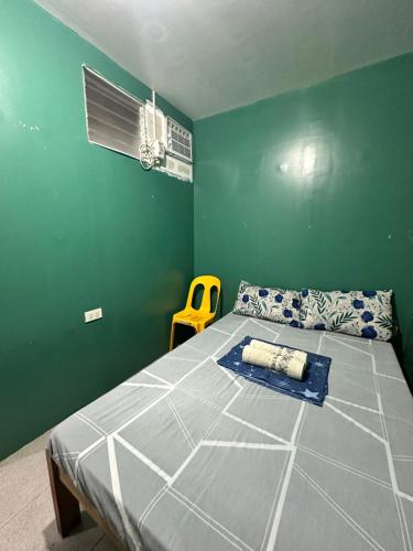 a bedroom with a bed and a yellow chair at Don Pedro shared bathroom 2 in Tacloban